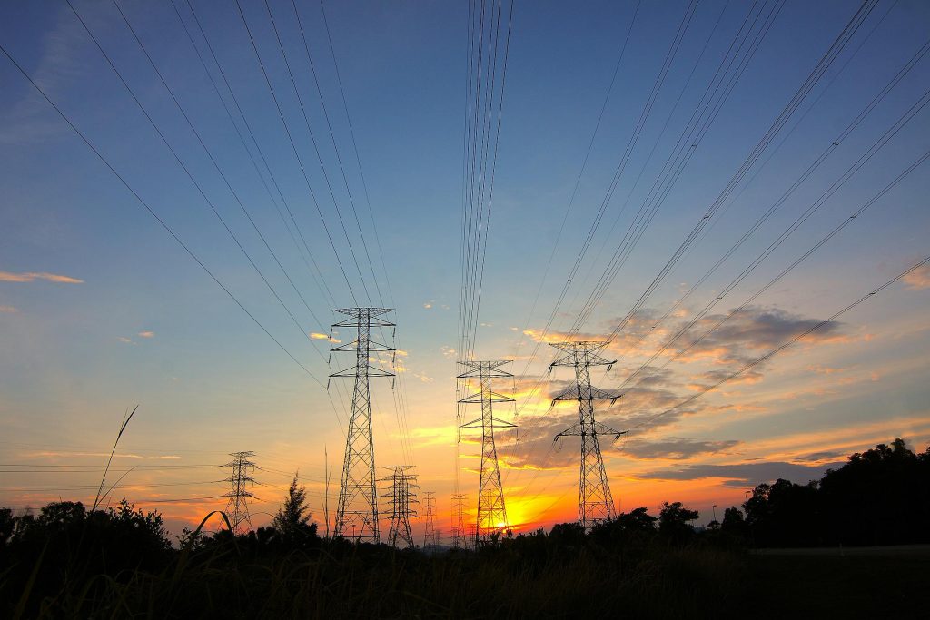 Silhouette of power lines against a dramatic sunset sky in a rural landscape.